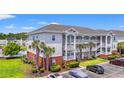Three-story condo complex with white railings and palm trees, surrounded by green lawns and parking spaces at 4142 Hibiscus Dr. # 20-202, Little River, SC 29566