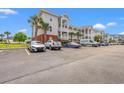 Condo building with a light exterior, multiple levels of private balconies, and a parking area at 4142 Hibiscus Dr. # 20-202, Little River, SC 29566