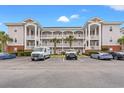 Three-story condo building showing private balconies, well-manicured landscaping, and ample parking at 4142 Hibiscus Dr. # 20-202, Little River, SC 29566