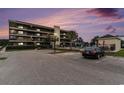 Condo complex at dusk showcasing balconies, parking area, swimming pool, and well-maintained landscaping, creating a serene environment at 4445 Kingsport Rd. # 101, Little River, SC 29566