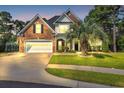 Attractive two-story brick home with manicured lawn, mature trees, a two-car garage, and dusk lighting at 4232 Pointer Ct., Myrtle Beach, SC 29579
