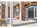 Inviting covered front porch with white columns, brick facade, and a stylish black front door at 4232 Pointer Ct., Myrtle Beach, SC 29579