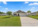 Single-story home with a well-maintained lawn, mature trees, and a driveway leading to a two-car garage at 568 Mossbank Loop, Longs, SC 29568