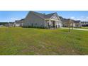 Side view of a gray house with lush green lawn, showcasing the home's exterior and landscaping at 8761 Nw Nashville Dr., Calabash, NC 28467