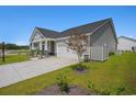 Gray exterior view of a single Gathering home, showing the driveway and landscaped front yard under a clear blue sky at 8761 Nw Nashville Dr., Calabash, NC 28467