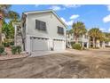 This stilt home offers a large 2-car garage with stairs leading to the front door and mature landscaping at 1125 Camellia Dr., Surfside Beach, SC 29575