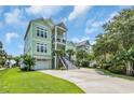 Beautiful two-story house with a concrete driveway, lush green lawn, and inviting exterior design in a coastal setting at 191 Grackle Ln., Pawleys Island, SC 29585