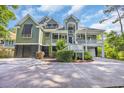 Two-story home featuring a spacious porch, landscaped front yard and multi-car garage underneath at 24 Jerry Ct., Pawleys Island, SC 29585