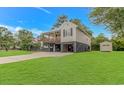 Side view of a coastal-style home with a wooden porch and a lush green lawn at 4600 Murrells Inlet Rd., Murrells Inlet, SC 29576