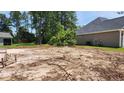Side view of a dirt-filled residential lot awaiting construction, surrounded by lush trees at 800 Stone Pine Ct., Loris, SC 29569