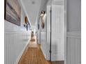 Charming hallway with coastal decor, beadboard, and wood floors leads to comfortably appointed bedrooms and living spaces at 1012 N Waccamaw Dr. # 1107, Murrells Inlet, SC 29576