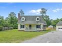 Charming two-story home with yellow siding and a lovely white porch surrounded by a well-manicured lawn at 124 Wicklow Way, Pawleys Island, SC 29585