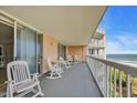 Spacious balcony with a great view of the ocean featuring white rocking chairs and a small table at 145 South Dunes Dr. # 308, Pawleys Island, SC 29585