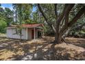 Exterior view of an outbuilding with a red metal roof nestled among mature trees at 1700 Longleaf Dr., Myrtle Beach, SC 29575