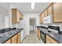 Galley kitchen featuring wood cabinets, black countertops, and tile flooring at 2061 Silvercrest Dr. # 7E, Myrtle Beach, SC 29579