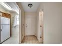 Hallway view with a white door, tile floors, and partial view into the kitchen with white appliances at 2309 Withers Dr. # 4, Myrtle Beach, SC 29577