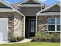 Inviting front entrance featuring a dark-colored door, stone accents, and well-maintained landscaping at 234 Rolling Woods Ct., Little River, SC 29566