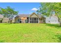 A spacious backyard featuring a screened porch, patio, and green lawn at 2487 Windmill Way, Myrtle Beach, SC 29579