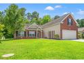 Traditional single Gathering home with a lush green lawn, mature trees, and attached garage at 2487 Windmill Way, Myrtle Beach, SC 29579