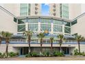 Exterior of the Avista Resort with a beautifully landscaped entrance with palm trees, plants, and blue-and-white decor at 300 N Ocean Blvd. # 122, North Myrtle Beach, SC 29582