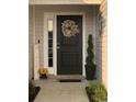 Inviting front door with seasonal wreath, complemented by potted plants and a charming welcome sign at 387 Blue Rock Dr., Longs, SC 29568