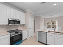 Modern kitchen boasts stainless steel appliances, white cabinetry, tile flooring, and a cozy breakfast bar at 5870 Longwood Dr. # 201, Murrells Inlet, SC 29576