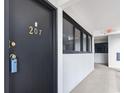 Condominium entryway featuring a black door marked with the gold number 207 and hallway with windows at 601 Mitchell Dr. # 207, Myrtle Beach, SC 29577