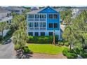 Captivating view of a blue two-story home with double balconies, surrounded by palm trees and green lawn at 573 S Dunes Dr., Pawleys Island, SC 29585