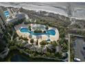 Aerial view of a large community pool with intricate design, surrounded by lush landscaping and seating areas at 9994 Beach Club Dr. # 2402, Myrtle Beach, SC 29572