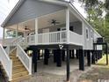 Inviting raised beach house with a covered porch, ceiling fans, and convenient access stairs at 1022 Waccamaw Dr., Conway, SC 29526