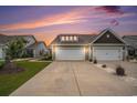 Charming home featuring a two-car garage and well-manicured lawn against a dramatic sunset at 1807 Berkley Village Loop, Myrtle Beach, SC 29579