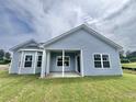 Back exterior view of home with blue siding, white trim, and a covered patio at 181 Norris Ln, Loris, SC 29569