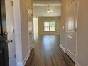 Inviting hallway with wood flooring, leading to a brightly lit living area with a ceiling fan at 185 Norris Ln, Loris, SC 29569