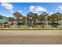 Charming colorful homes with white picket fences, palm trees, and stairs leading to covered porches at 22 Ocean Blvd. N, Surfside Beach, SC 29575