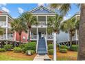 Charming colorful homes with palm trees and stairs leading to covered porches, enhanced curb appeal at 22 Ocean Blvd. N, Surfside Beach, SC 29575