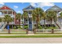 Charming colorful homes with white picket fences, palm trees, and stairs leading to covered porches at 22 Ocean Blvd. N, Surfside Beach, SC 29575