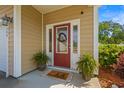 Inviting front entryway with a red door, decorative wreath, sidelights, and potted plants at 309 Foxpath Loop, Myrtle Beach, SC 29588