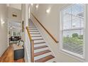 Bright staircase with white risers, wood treads, wooden handrail, window, and wall sconces at 309 Foxpath Loop, Myrtle Beach, SC 29588