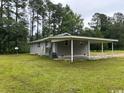 A wide shot of the side of the home with carport and tree-lined landscape at 321 Circle Heights Dr., Loris, SC 29569
