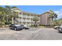 A multi-story condo exterior with a parking lot, palm trees, and exterior staircases at 4721 Hibiscus Dr. # 3-302, Little River, SC 29566