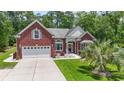 Beautiful single-story red brick home with a well-maintained lawn, a two-car garage, and mature landscaping at 499 Trestle Way, Conway, SC 29526
