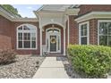 Inviting front entrance with a decorative wreath, white rocking chair, and manicured bushes at 499 Trestle Way, Conway, SC 29526