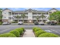 Three-story condo building featuring white balconies, brick accents, palm trees, and convenient parking at 6015 Catalina Dr. # 634, North Myrtle Beach, SC 29582
