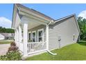 Side of home featuring a cozy covered porch, white columns, and beautiful green grass, perfect for relaxing at 775 Harrison Mill St., Myrtle Beach, SC 29579