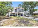 Charming stilt home featuring a screened porch, driveway, and lush surrounding trees at 910 N Dogwood Dr., Surfside Beach, SC 29575