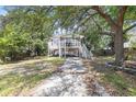 Charming stilt home featuring a screened porch, driveway, and lush surrounding trees at 910 N Dogwood Dr., Surfside Beach, SC 29575