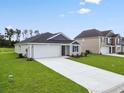 Inviting one-story home with a long driveway and landscaping leading to the attached two-car garage at 1004 Kinness Dr., Conway, SC 29527