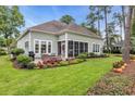 Well-maintained backyard featuring a patio with outdoor seating, a screened-in porch, and colorful flower beds at 124 Turtle Creek Dr., Pawleys Island, SC 29585