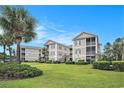 Condo building exterior with lush landscaping, large palm trees, and well-manicured lawn at 2000 Cross Gate Blvd. # 202, Surfside Beach, SC 29575
