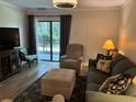 A furnished living room includes a sliding glass door, a sofa, a chair, and an ottoman at 5001 Little River Rd. # W101, Myrtle Beach, SC 29577